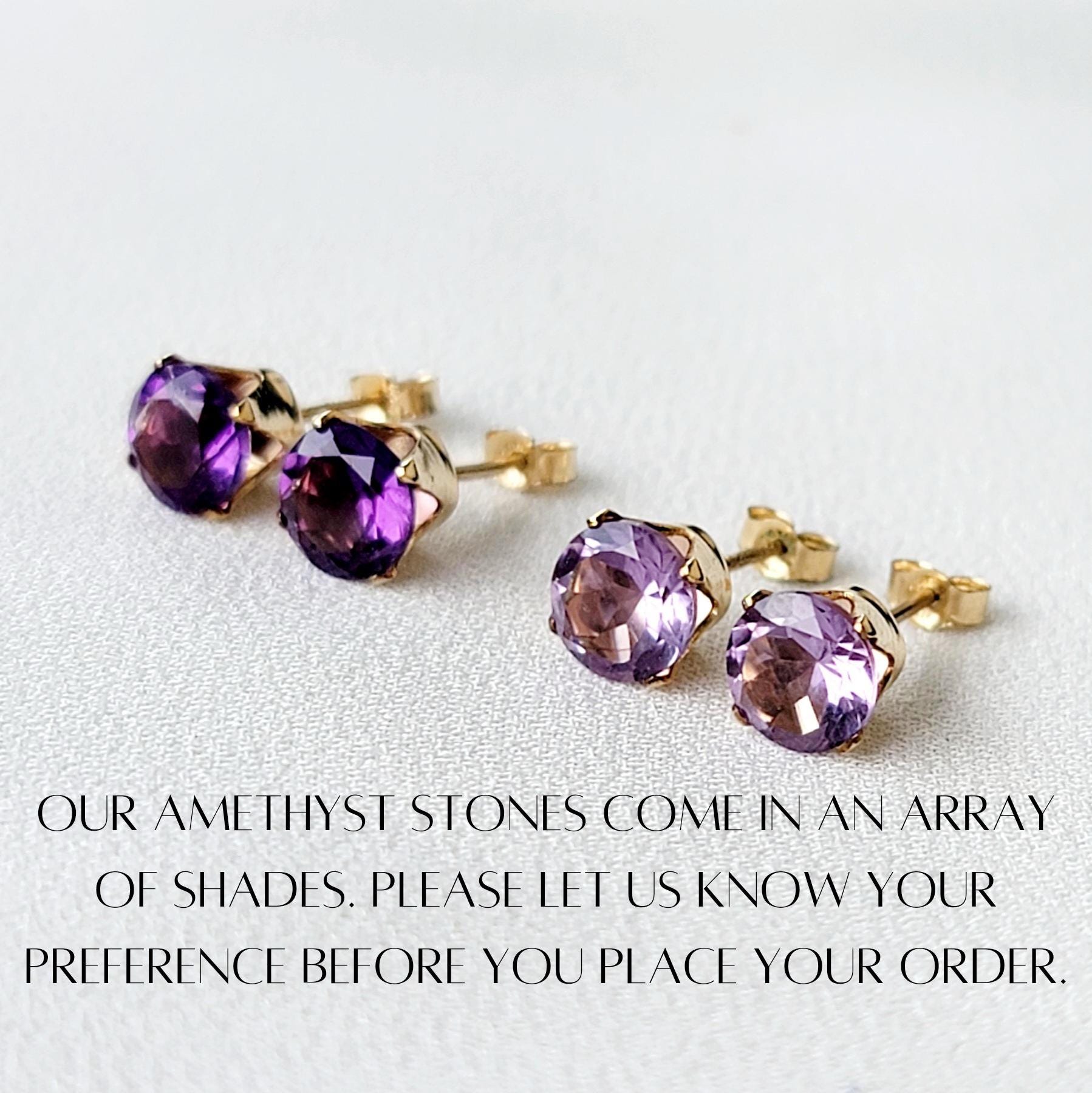 Three pairs of amethyst stud earrings with gold settings. The amethyst stones are different shades of purple. The text below the earrings reads: &#39;OUR AMETHYST STONES COME IN AN ARRAY OF SHADES. PLEASE LET US KNOW YOUR PREFERENCE BEFORE YOU PLACE YOUR ORDER.&#39;