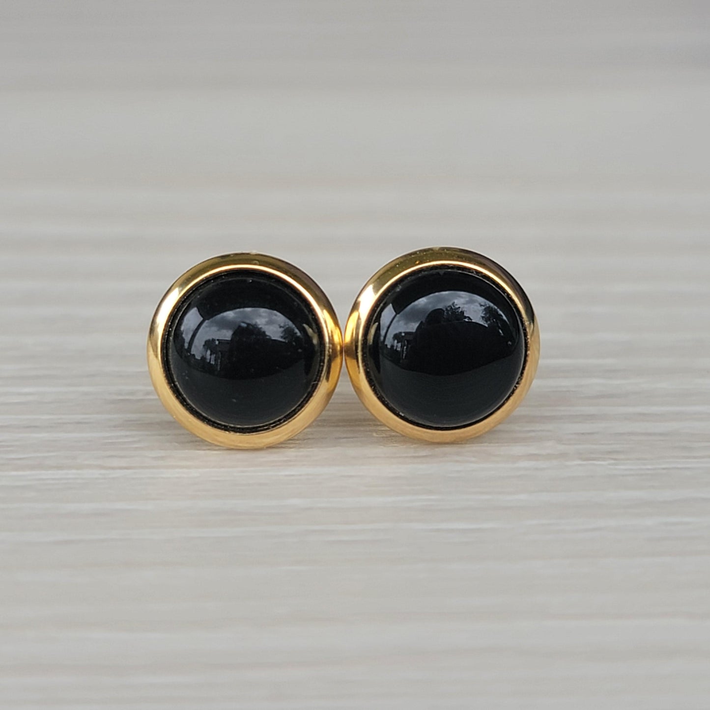 A pair of gold stud earrings with black round onyx gemstones
