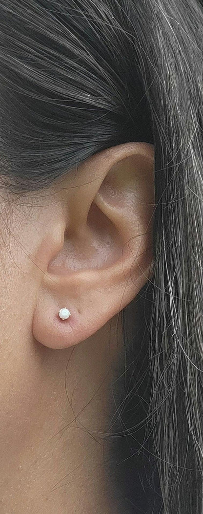 May include: A close-up of a person&#39;s ear with a small, 2mm white opalite earring.