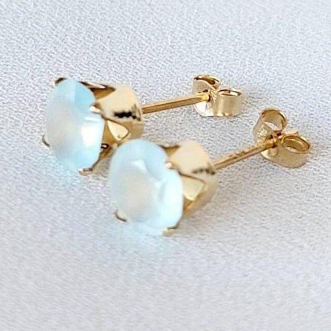 A pair of gold stud earrings with light blue chalcedony round faceted gemstones