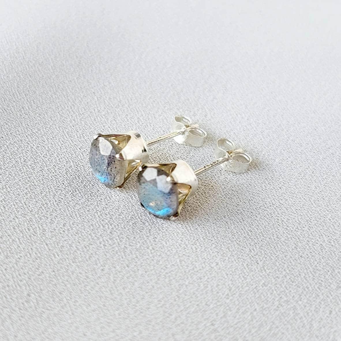 A pair of silver stud earrings with round, iridescent blue-grey gemstones