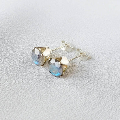 A pair of silver stud earrings with round, iridescent blue-grey gemstones