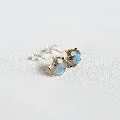 A pair of silver stud earrings with round, iridescent blue and gray labradorite gemstones.