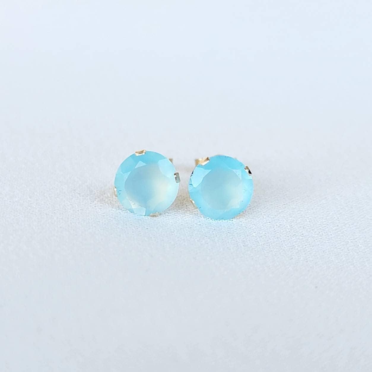 A pair of gold stud earrings with light blue chalcedony round faceted gemstones
