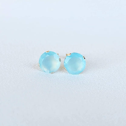 A pair of gold stud earrings with light blue chalcedony round faceted gemstones