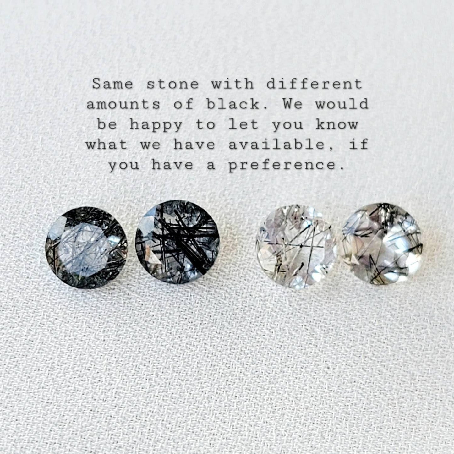 Four round, clear quartz stones with black inclusions. The stones are arranged in a row from left to right. The stones have varying amounts of black inclusions. The text below the stones reads: 'Same stone with different amounts of black. We would be happy to let you know what we have available, if you have a preference.'