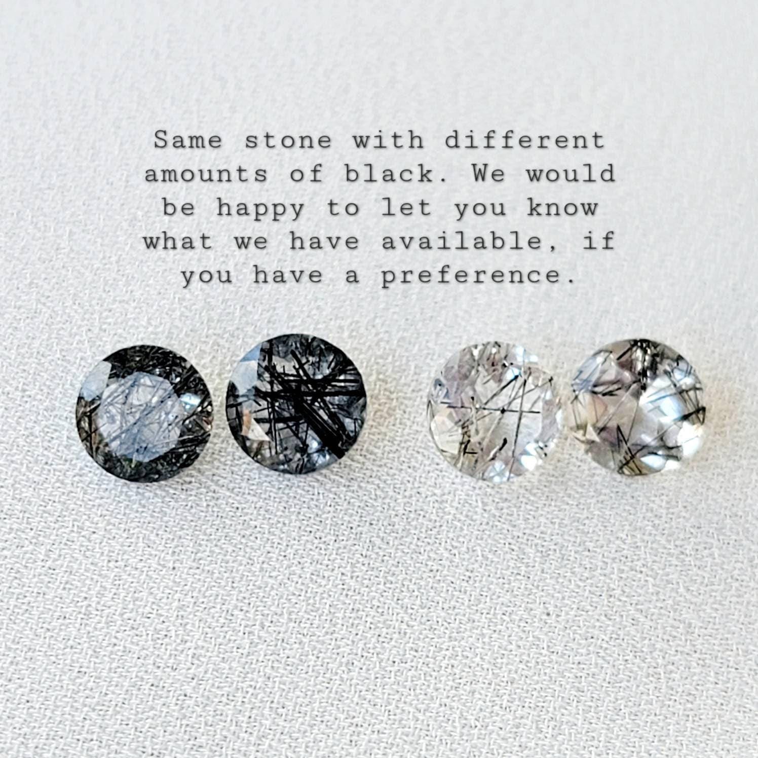 Four round, clear quartz stones with black inclusions. The stones are arranged in a row from left to right. The stones have varying amounts of black inclusions. The text below the stones reads: 'Same stone with different amounts of black. We would be happy to let you know what we have available, if you have a preference.'