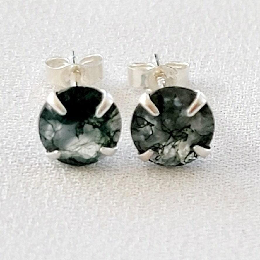 A pair of silver stud earrings with round green moss agate stones. The stones have a marbled pattern from the moss growing through the clear crystal.
