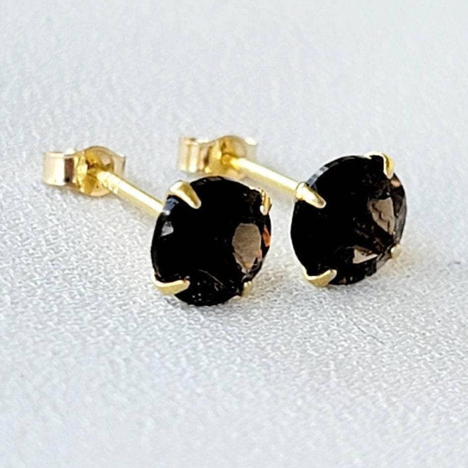 May include: A pair of gold stud earrings with round, dark brown smoky quartz gemstones.