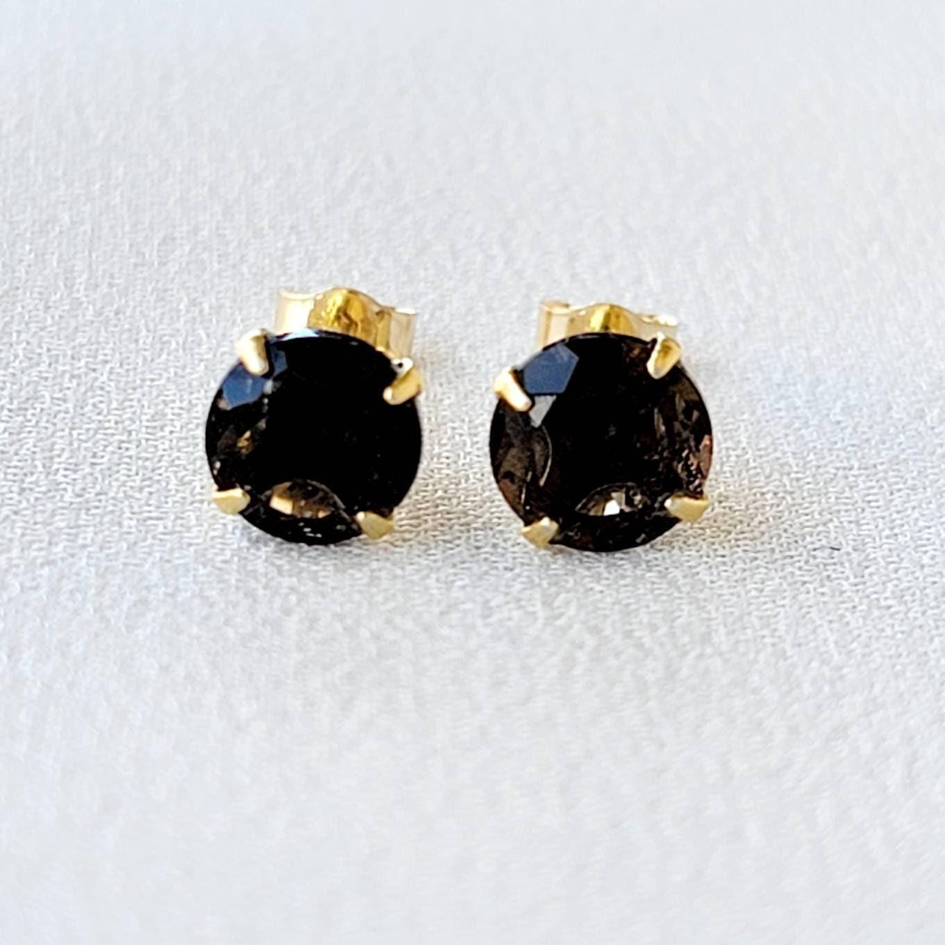 May include: A pair of gold stud earrings with round, dark brown smoky quartz gemstones.