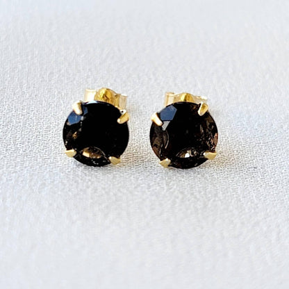 May include: A pair of gold stud earrings with round, dark brown smoky quartz gemstones.