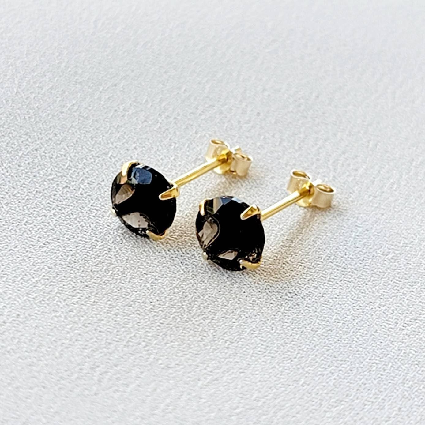 May include: A pair of gold stud earrings with round, dark brown smoky quartz gemstones.