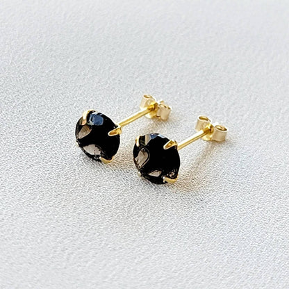 May include: A pair of gold stud earrings with round, dark brown smoky quartz gemstones.