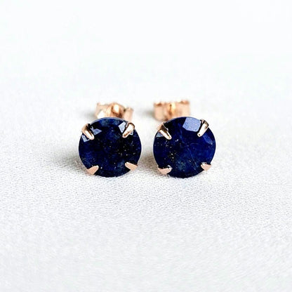 A pair of rose gold stud earrings with round blue lapis lazuli gemstones.