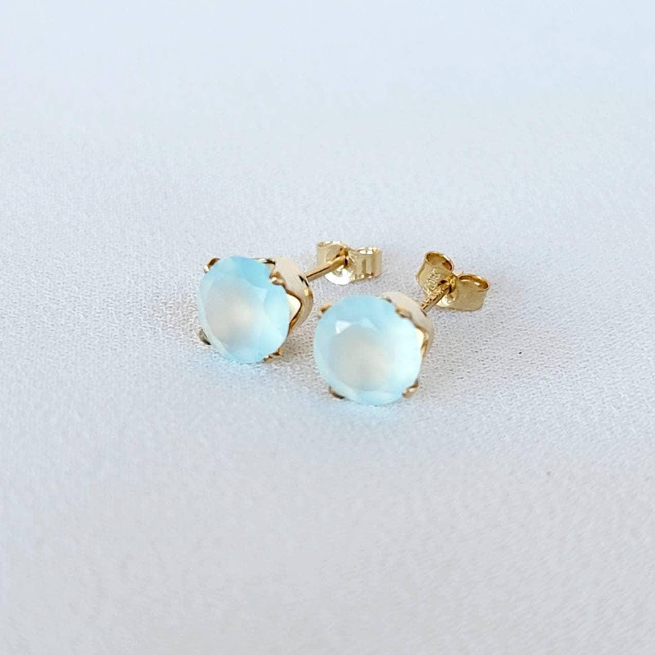 A pair of gold stud earrings with light blue chalcedony round faceted gemstones