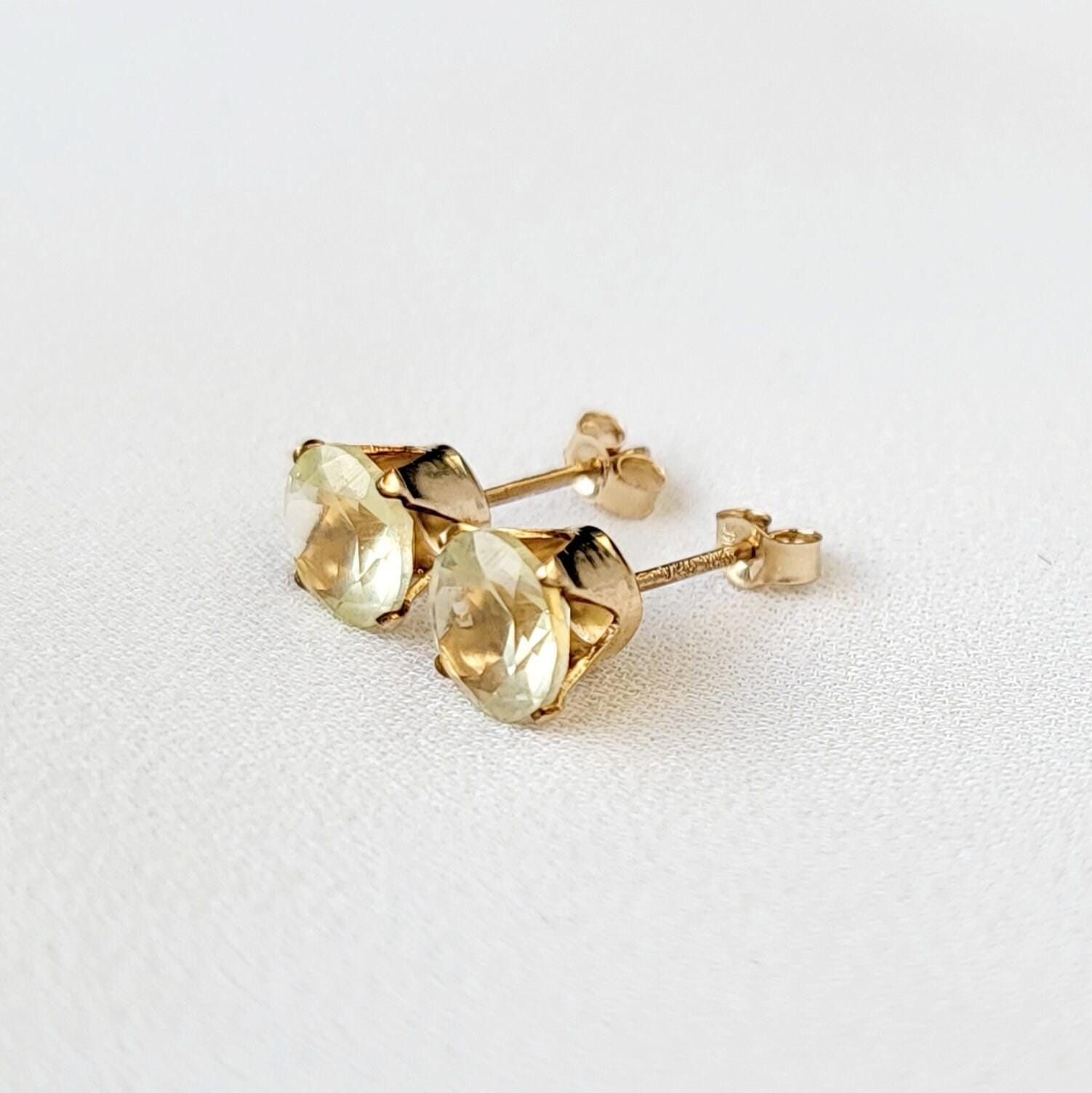 A pair of gold earrings with round shaped light yellow lemon quartz gemstones