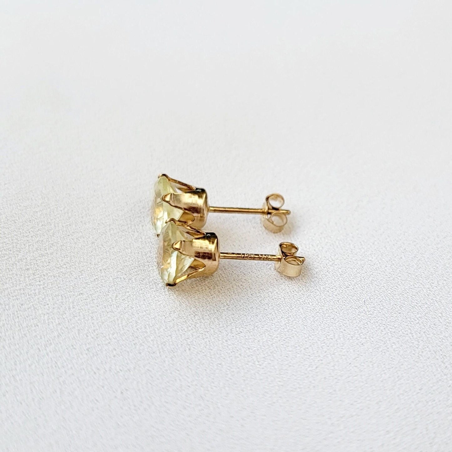 A pair of gold earrings with round shaped light yellow lemon quartz gemstones