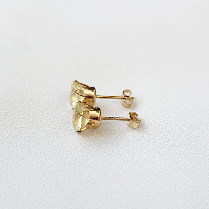 A pair of gold earrings with round shaped light yellow lemon quartz gemstones