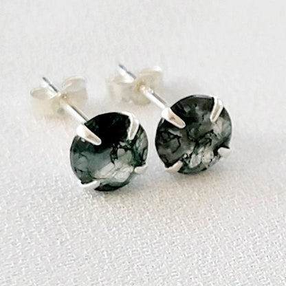 A pair of silver stud earrings with round green moss agate stones. The stones have a marbled pattern from the moss growing through the clear crystal.
