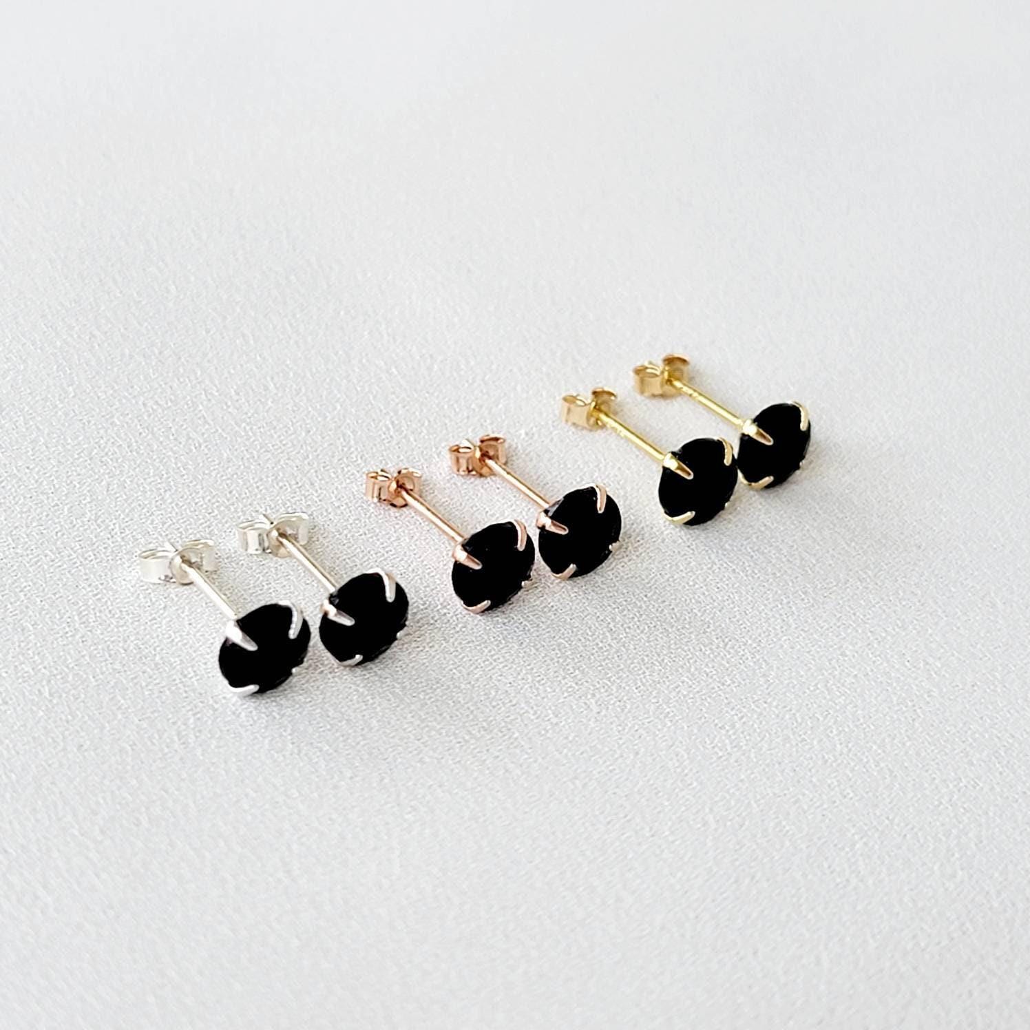 A pair of gold stud earrings with round faceted black onyx gemstones.
