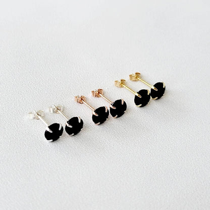 A pair of gold stud earrings with round faceted black onyx gemstones.
