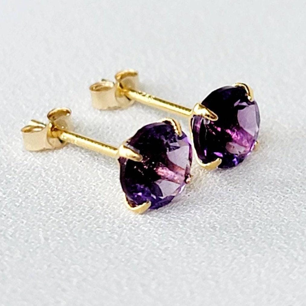 A pair of gold stud earrings with purple amethyst gemstones