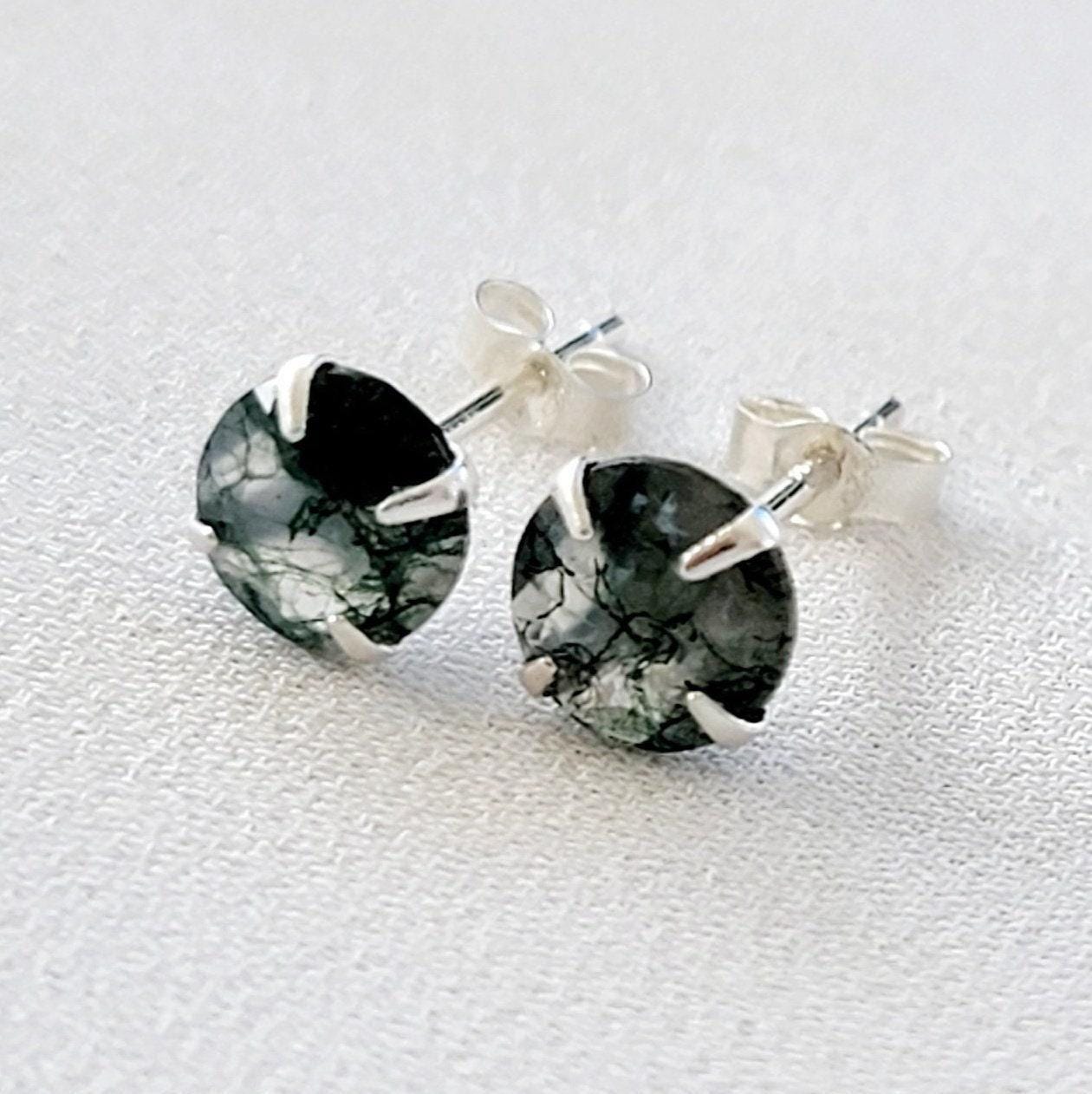 A pair of silver stud earrings with round green moss agate stones. The stones have a marbled pattern from the moss growing through the clear crystal.