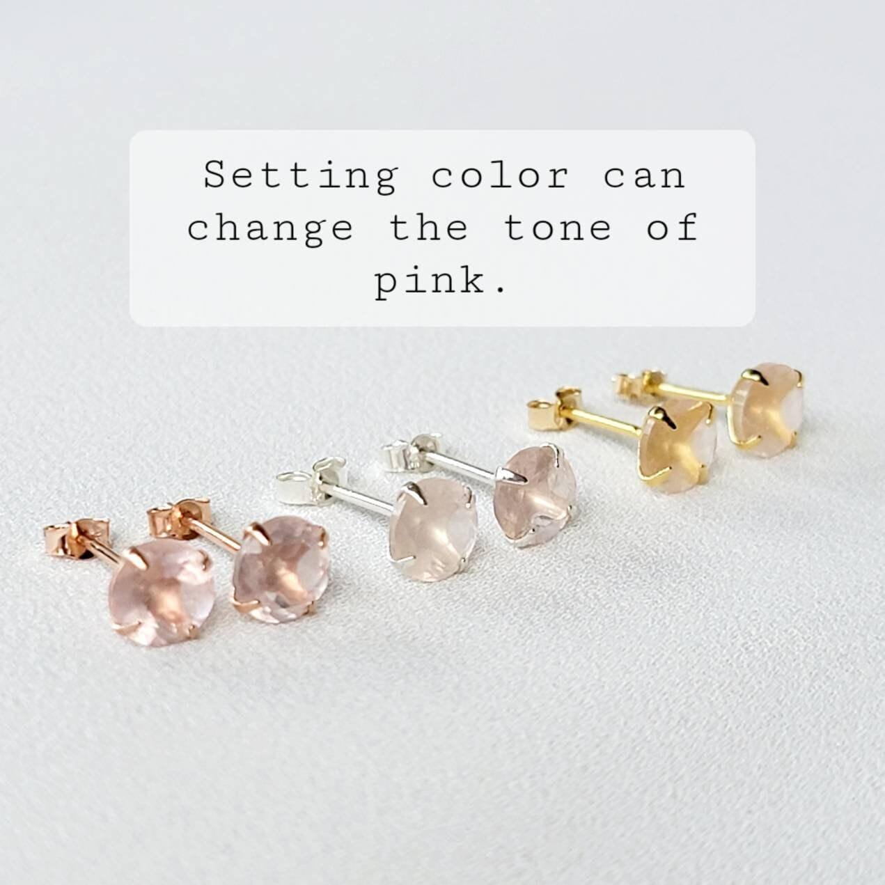 Three pairs of rose quartz stud earrings in gold, rose gold, and silver settings.  The text overlay reads: 'Setting color can change the tone of pink.'