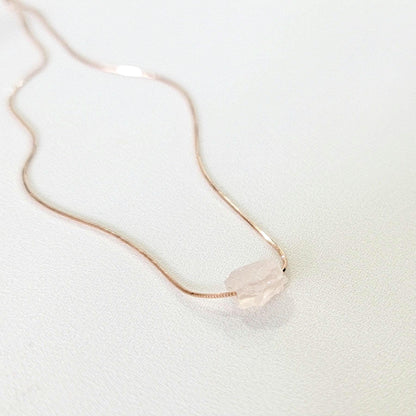 An uncut rough rose quartz stone on a 18k rose gold plated sterling silver necklace. other necklace colors are available.