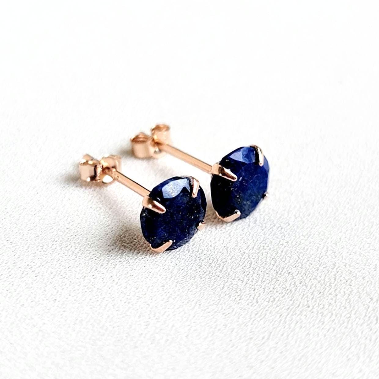 A pair of rose gold stud earrings with dark blue gemstone lapis lazuli.